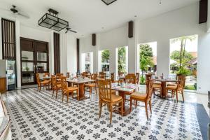 uma sala de jantar com mesas, cadeiras e janelas em Inna Bali Heritage Hotel em Denpasar
