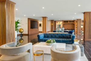 a living room with a blue couch and chairs at Cambria Hotel Detroit Downtown in Detroit