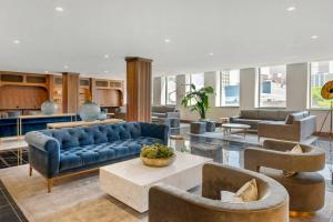 a living room with a blue couch and chairs at Cambria Hotel Detroit Downtown in Detroit