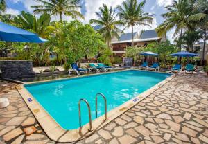 a pool at a resort with chairs and umbrellas at Le Palmiste Resort & Spa in Trou aux Biches
