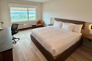 a hotel room with a bed and a desk and a window at Quality Inn & Suites Temiscouata-sur-le-Lac in Notre-Dame-du-Lac