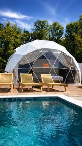a tent and two chairs next to a swimming pool at Kupolica glamping dome in Brčko +8 photos