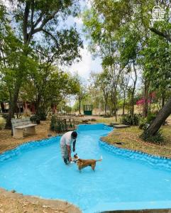 a man playing with a dog on a blue pool at The Hideaway Hosur by evaddo stays in Hosūr +144 photos