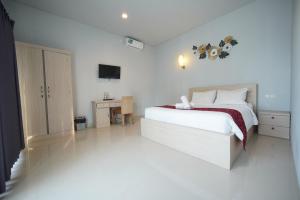 a white bedroom with a bed and a desk at The Joy Rooms Penida in Nusa Penida