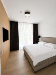 a bedroom with a white bed and a large window at Maria Blick in Maria Wörth