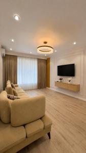 a living room with a couch and a flat screen tv at High Town City in Lunacharskiy Bekati
