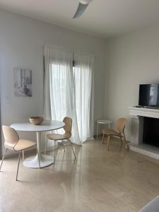 a white living room with a table and chairs at Anna Coast Apartment in Agia Anna