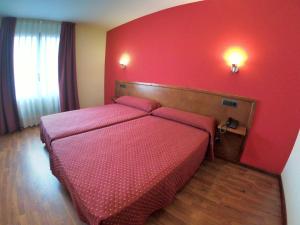 a bedroom with a bed with a red wall at Hotel Virgen de Covadonga in Cangas de Onís
