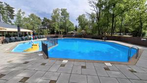 a person on a slide in a swimming pool at Sfeervol Veluws Meerhuisje luxe gezinschalet aan het water met opgemaakte bedden en handdoeken in Nunspeet