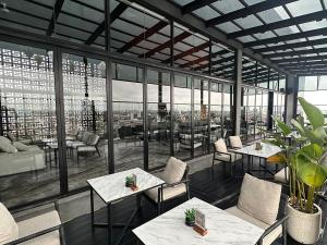 REZ Hotel Semarang في سيمارانغ: مطعم به طاولات وكراسي ونوافذ