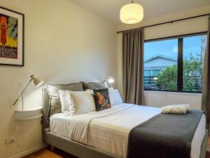 a bedroom with a large bed with a window at Kowhai Cabin - Serene Scandi Escape in Hokitika in Hokitika
