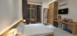 a bedroom with a white bed and a television at Hotel Suối Cao in Phú Quốc +13 photos