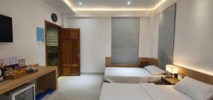 a hotel room with two beds and a desk and a room at Hotel Suối Cao in Phú Quốc