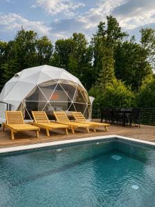 a tent and chairs next to a swimming pool at Kupolica glamping dome in Brčko