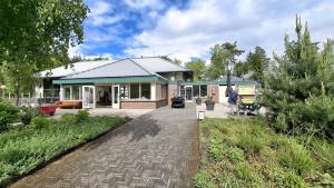 a house with a brick walkway in front of it at Sfeervol Veluws Meerhuisje luxe gezinschalet aan het water met opgemaakte bedden en handdoeken in Nunspeet