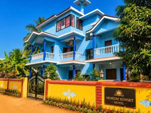 a blue house with a sign in front of it at Morjim Sunset Guesthouse- Apartments with Kitchen & AC Rooms in Morjim