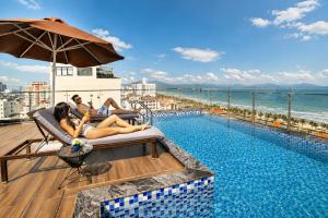 two women laying in chairs next to a swimming pool at Halina Hotel and Apartment in Danang