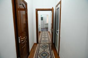 a hallway with an open door with a rug on the floor at Meyman House in Karakol