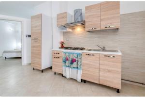 a kitchen with wooden cabinets and a sink at Villa Blu Dea room & apartment in Torre Lapillo