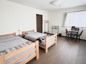 a bedroom with two beds and a table with chairs at Oyado SORARURI in Yakushima