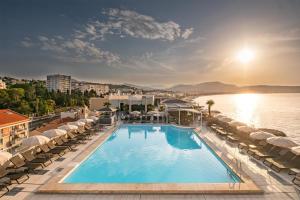 ein Schwimmbecken mit Liegestühlen und Wasser in der Unterkunft Radisson Blu Hotel Nice in Nizza