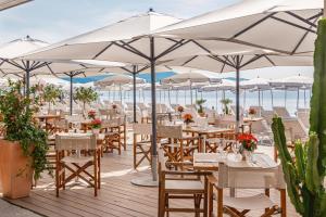 ein Restaurant mit Tischen und Sonnenschirmen am Strand in der Unterkunft Radisson Blu Hotel Nice in Nizza