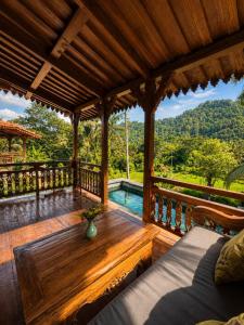 a porch with a wooden table and a swimming pool at Alamdhari Villa Sidemen in Sidemen