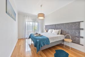 a bedroom with a bed with a blue blanket on it at Beach Sunset - Apartment Ocean in Vila Nova de Gaia +27 photos