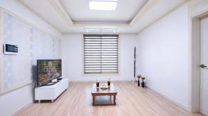 a living room with a tv and a table at Samcheok Jisu Pension in Samcheok
