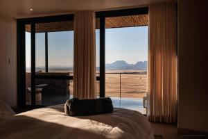 a bedroom with a bed and a large glass window at Rostock Ritz Desert Lodge in Cha-re
