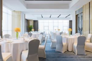 a banquet room with white tables and white chairs at Wanda Realm Jiangmen in Jiangmen +76 photos