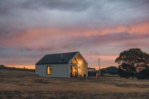 a small white house in a field at sunset at Glenbosch - Cottage One in Beechworth