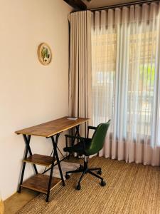 a desk and a green chair in a room with a window at Siki's Cactus Hideaway in Mmokolodi
