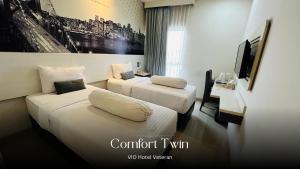 a hotel room with two beds and a tv at Vio Veteran in Bandung