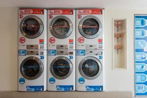 four washing machines are lined up against a wall at New Town Resort Suites at Pyramid Tower in Subang Jaya