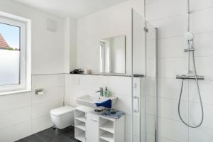 a white bathroom with a shower and a sink at Haus Seeluft - W3 in Butjadingen +10 photos