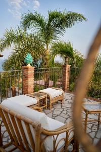 a patio with chairs and tables and palm trees at Tenuta Bellassai in SantʼAlessio Siculo