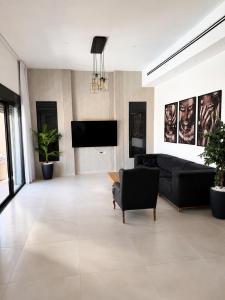 a living room with a couch and a flat screen tv at וילת צאלים in Yeroẖam