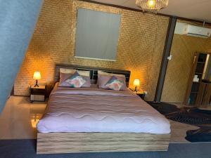 a bedroom with a large bed with two lamps at Alisa Villa, Ubon Cottage in Ban Pla Duk