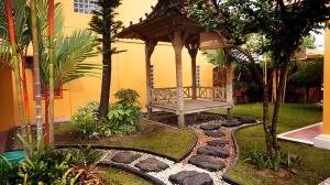 a gazebo with a bench in a garden at Devega Homestay in Yogyakarta