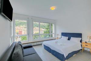 a bedroom with a bed and a couch and windows at Casa Cupido Locarno - Happy Rentals in Locarno