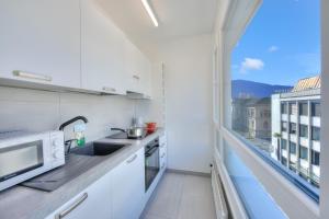 a kitchen with white cabinets and a large window at Casa Cupido Locarno - Happy Rentals in Locarno