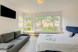 a bedroom with a bed and a couch and windows at Casa Cupido Locarno - Happy Rentals in Locarno +13 photos