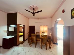 a dining room with a table and chairs and a ceiling fan at Happy Home Varkala in Varkala