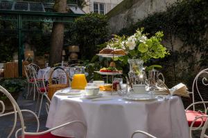 a table with a white table cloth and flowers on it at Hôtel Des Marronniers in Paris