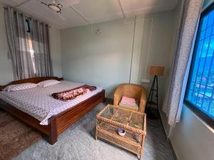 a bedroom with a bed and a chair and a window at BeeHive Homestay in Hāflong