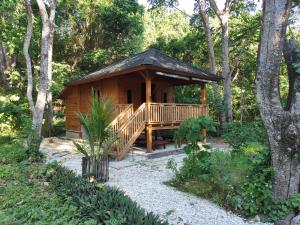a wooden cabin with a deck in the woods at Air Wontu in Moyo Island