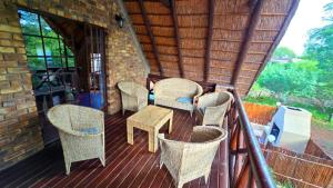 a porch with wicker chairs and a table on a building at Indlovu Inn in Marloth Park