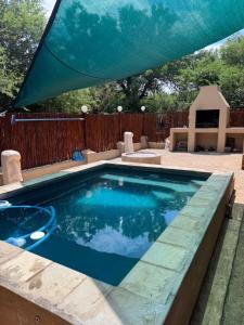 a swimming pool in a backyard with a blue umbrella at Indlovu Inn in Marloth Park