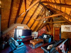 a living room with leather couches and a tv at Indlovu Inn in Marloth Park